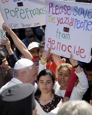 A women holds a placard as Pope Francis greets migrants and refugees at the Moria refugee camp near the port of Mytilene