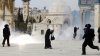 Palestinská žena prochází mezi bojujícími tábory Palestinců a Izraelců. Policie je rozhání slzným plynem