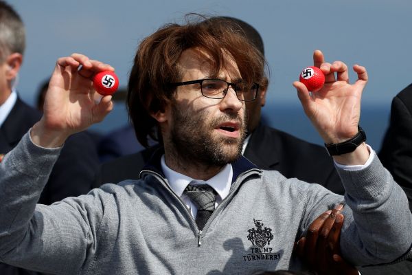 Aktivista, kter&yacute; p�i&scaron;el na tiskovou konferenci Donalda Trumpa - s golfov&yacute;mi m&iacute;�ky se svastikou.