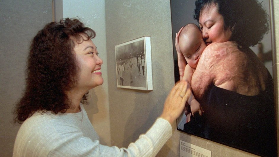Kim Phuc na snmku z roku 1996 se dv na svou fotografii, na n dr v nru syna.