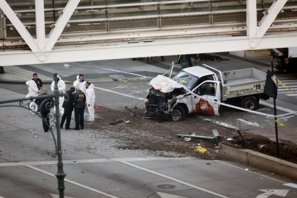 Investigators stand near the wreckage of a Home Depot truck at an overpass for Stuyvesant High School