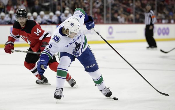 Vancouver Canucks right wing Brock Boeser (6) tries to control the puck as New Jersey Devils center Adam Henrique (14) looks on during the first period of an NHL hockey game