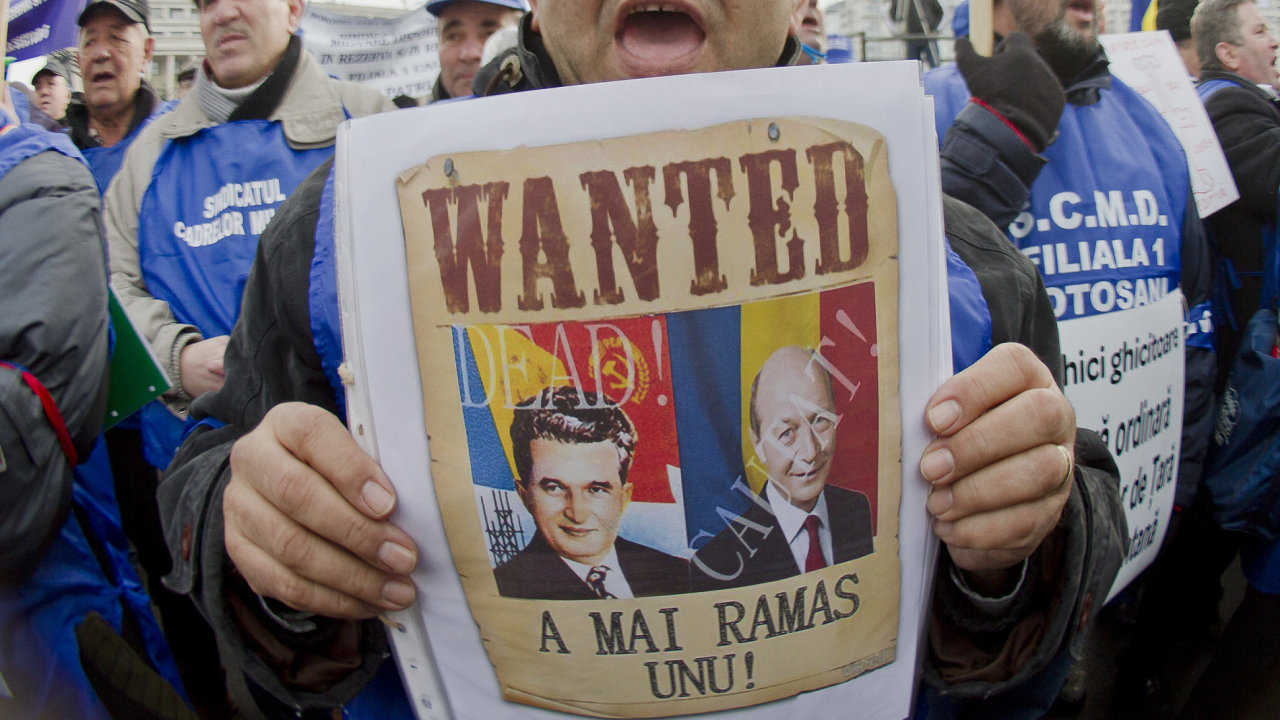 Rumunsk demonstrant dr plakt s portrty bvalho dikttora Ceauceska a souasnho prezidenta Baseska a npisem 