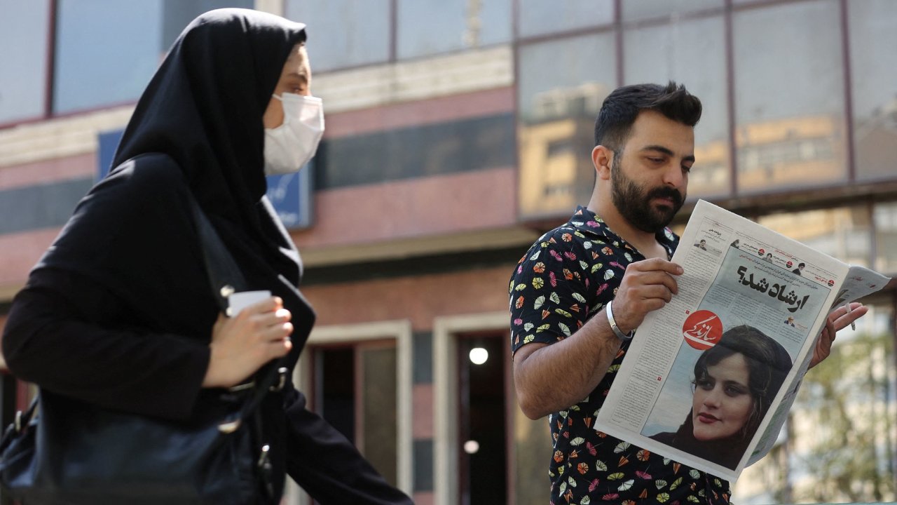 Muž drží noviny s portrétem dvaadvacetileté ženy, kterou zadržela mravnostní policie. Ženu podle svìdkù zbila.
