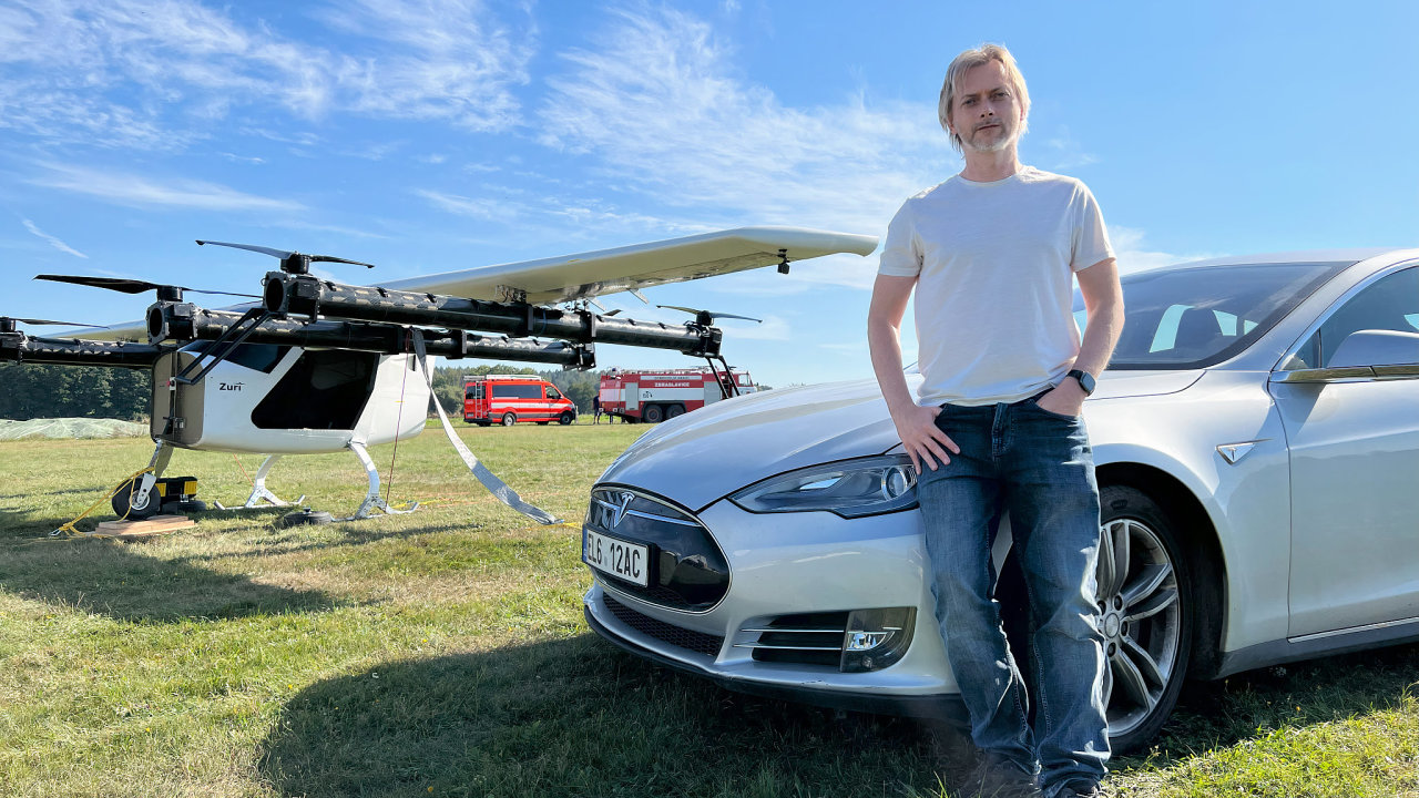 Technologick podnikatel Michal Illich a jeho deset let star Tesla Model S. V pozad prototyp letounu s vertiklnm vzletem a pistnm Zuri.