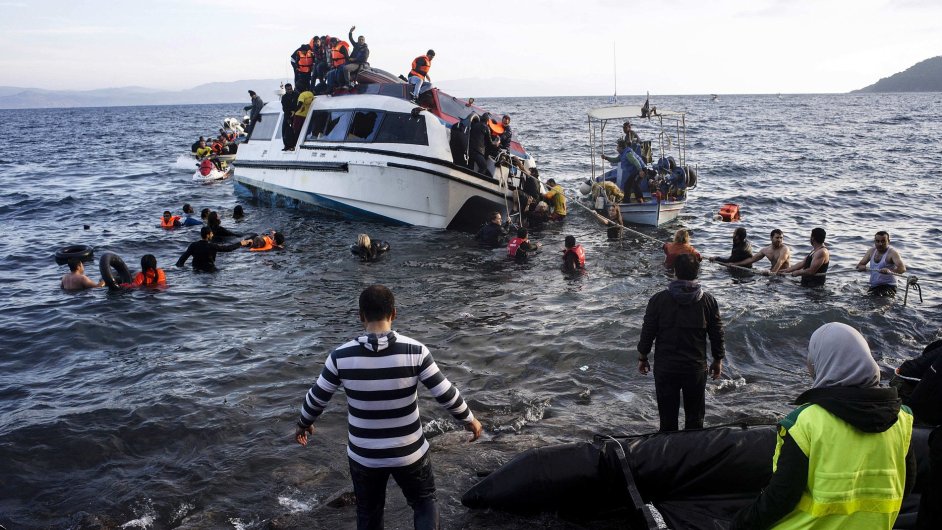 Volunteers and local residents help refugees and migrants to disembark from a small vessel after their arrival in Skala Sykaminias on the northeastern Greek island of Lesbos on Friday