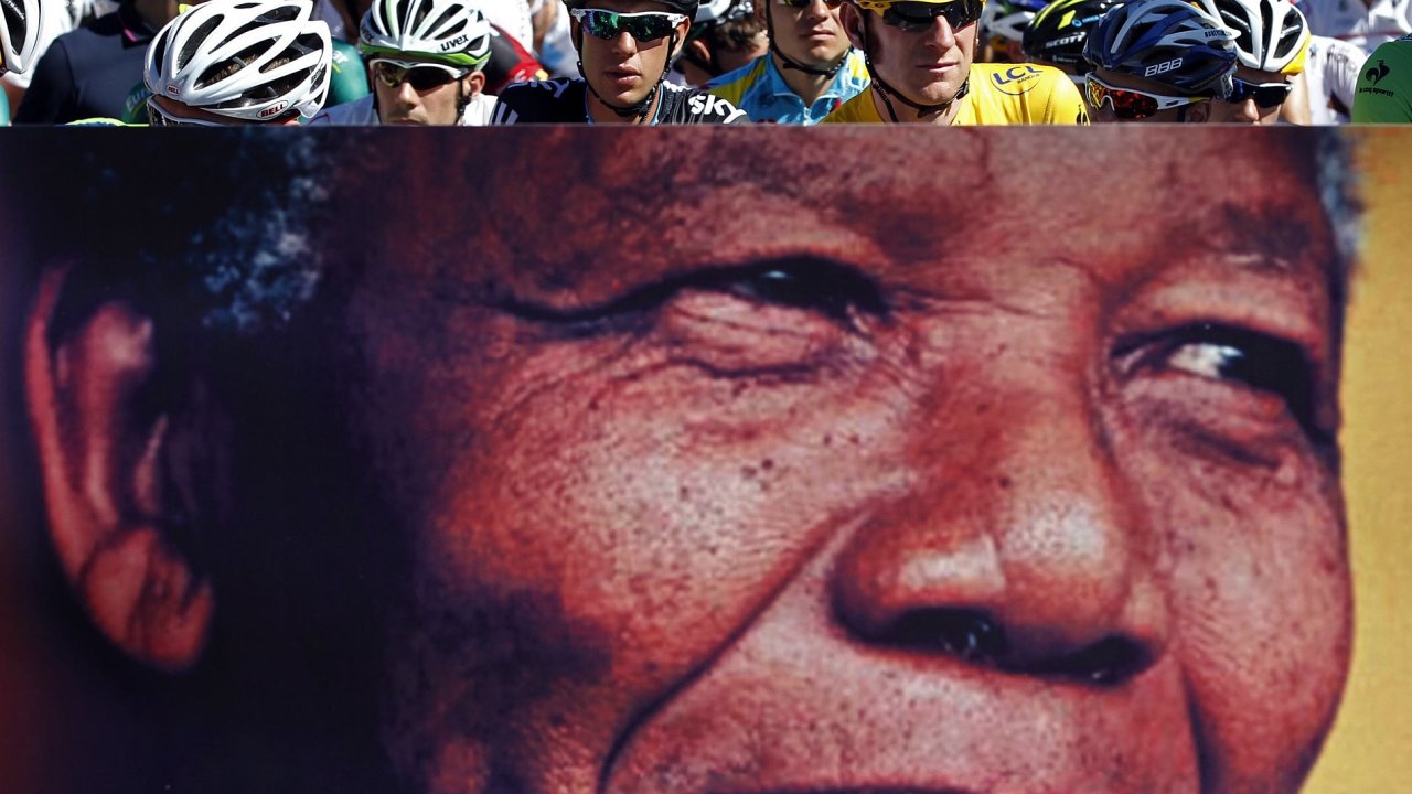 Cyklist ekaj na startu Tour de France ped plaktem s portrtem Nelsona Mandely