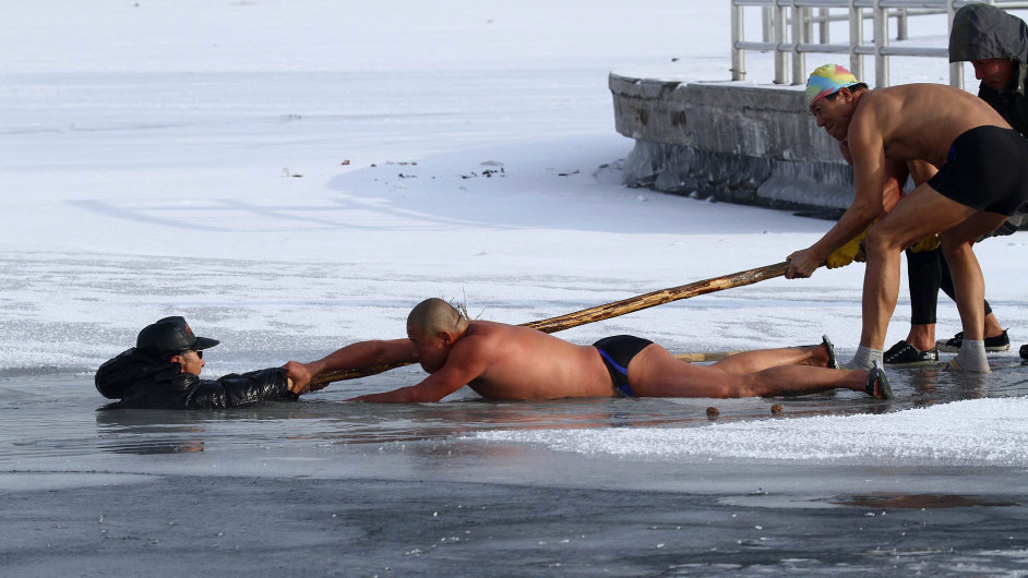 Winter swimmers (R) try to pull an elderly man (L) out of icy waters after he was trapped in a partially frozen lake at a park in Changchun