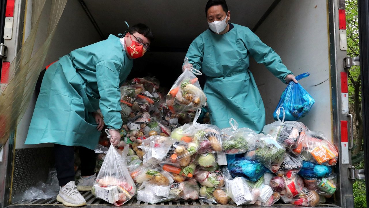Pracovníci v ochranných oblecích tøídí na nákladním autì pytle se zeleninou a potravinami, aby je mohli rozdat obyvatelùm obytného komplexu bìhem lockdownu v Šanghaji.