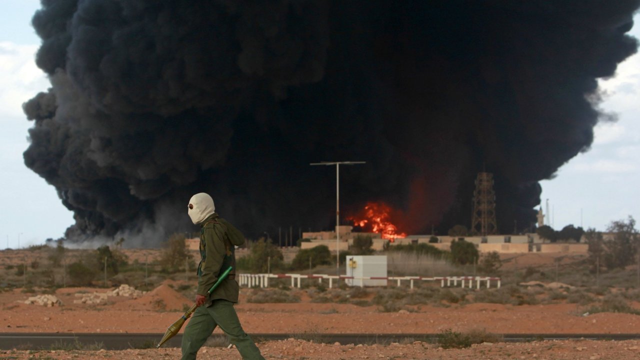 Ilustran foto - Jeden z rebel prochz kolem ponienho ropnho terminlu u libyjskho msta Al-Sedr.