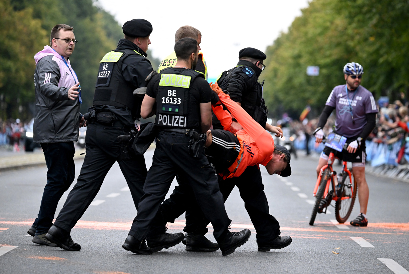 Berln, aktivista ze skupiny na ochranu klimatu "Posledn generace" je odnen policisty bhem protestn akce ped startem maratonu