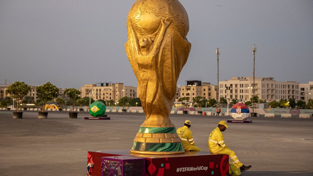 FIFA World Cup Qatar 2022 Preview - Lusail, Qatar - November 10, 2022 Workers sit beside a replica of the World Cup outside Lusail Stadium ahead of the World Cup REUTERS/Marko Djurica