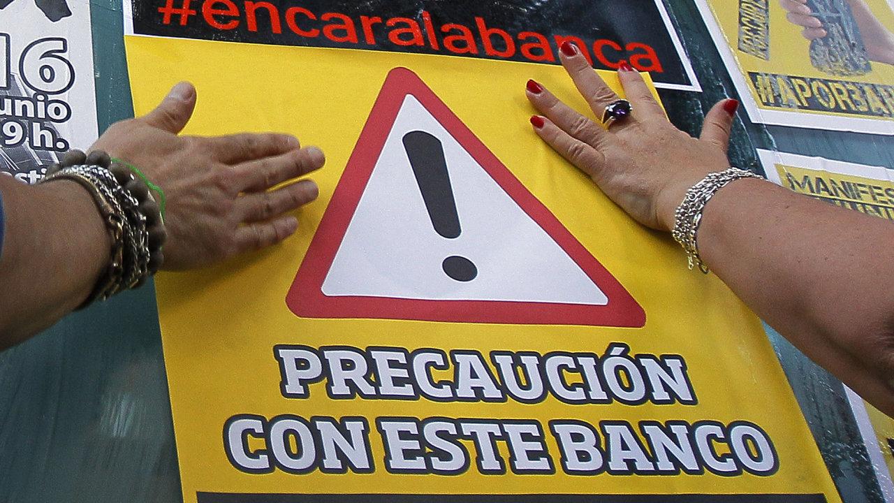Demonstranti nalepuj na budovu tamnho domu Bankia plakt s npisem: 
