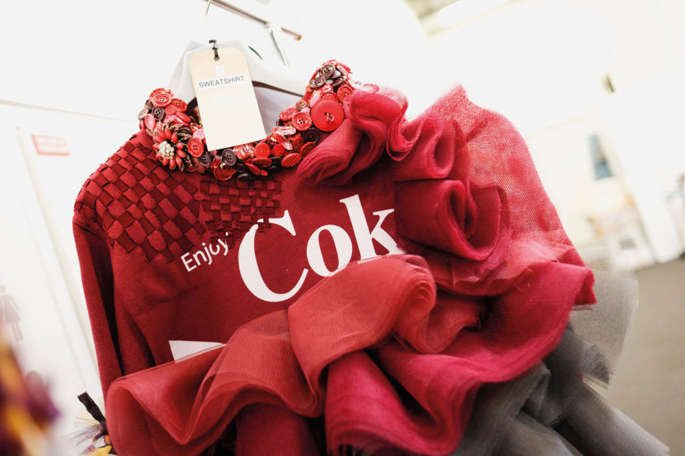 Součástí prvního modelu značky na červencové přehlídce haute couture byla vínově rudá mikina s logem Coca-Coly. Součástí prvního modelu značky na červencové přehlídce haute couture byla vínově rudá mikina s logem Coca-Coly.