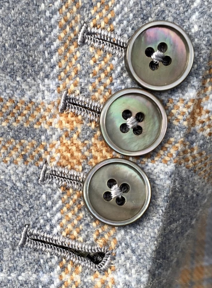 Detail rukávu saka. Hedvábnou nití ručně vyšívané knoflíkové dírky a hedvábnou nití přišívané perleťové knoflíčky.