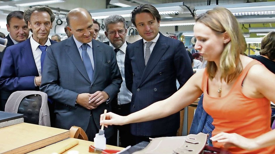 French Finance Minister Pierre Moscovici (2ndL) and Axel Dumas (2ndR), co-chief executive of French luxury goods group Hermes, meet employees who work on handbags as they visit the Hermes factory in S