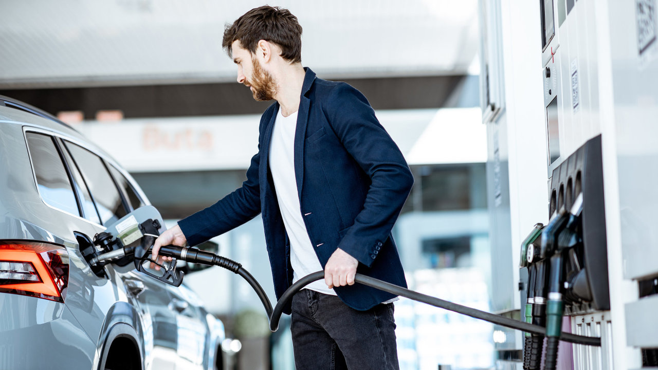 Businessman refueling his luxury car holding filling gun at the gas station