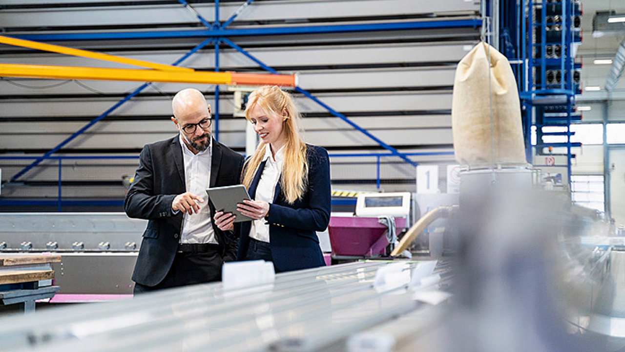 Businessman and businesswoman with tablet discussing in factory