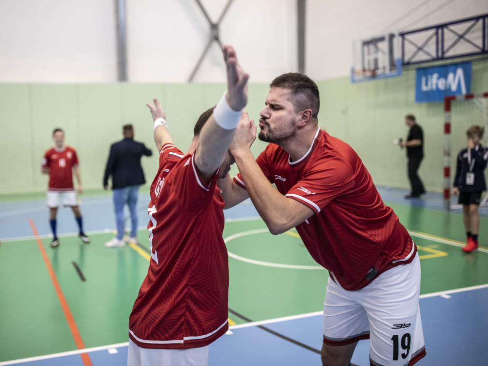 Kaplan Arcibiskupského gymnázia v Kroměříži Petr Káňa zvaný Kaňour líbá pro štěstí před zápasem říčanského faráře, kolegu z týmu a organizátora turnaje Konstantina Petra Mikolajeka řečeného Kosťa.