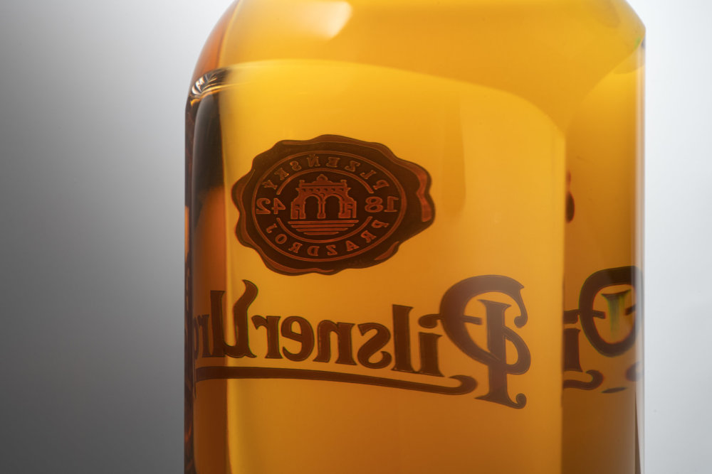 Pivní lahev Pilsner Urquell od designéra Michala Froňka, sklárny Moser a manufaktury Bohematic