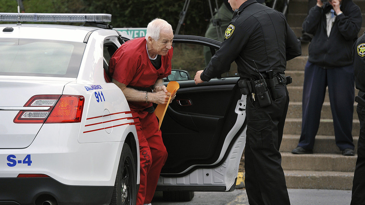 Obvinn Jerry Sandursky vystupuje z policejnho auta.