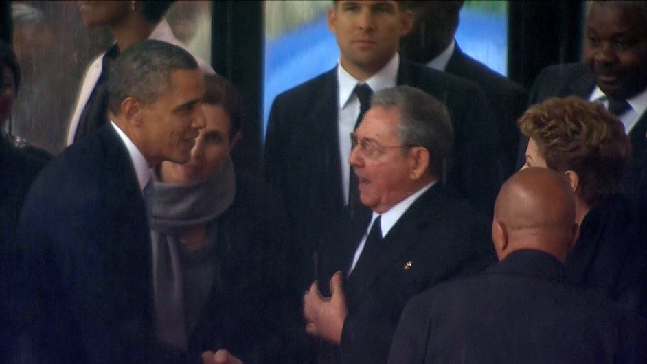 Sledovan gesto. Podn rukou prezident Obamy a Castra pi piet za Nelsona Mandelu v JAR.