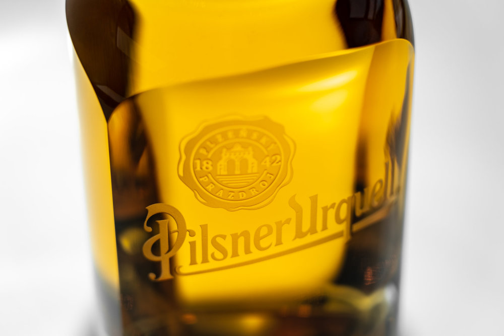 Pivní lahev Pilsner Urquell od designéra Michala Froňka, sklárny Moser a manufaktury Bohematic