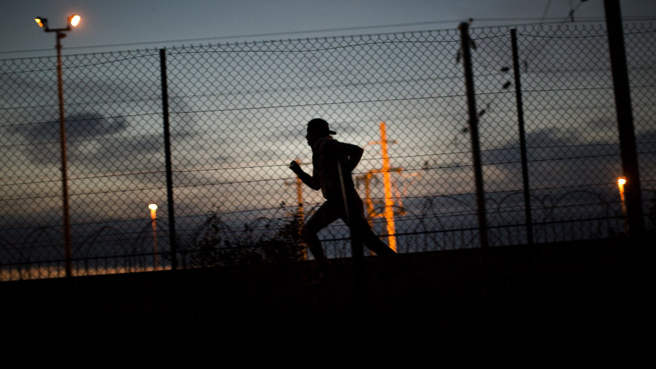 Uprchlík v mìstì Calais utíká poté, co pøelezl plot vedoucí k tunelu do Británie.