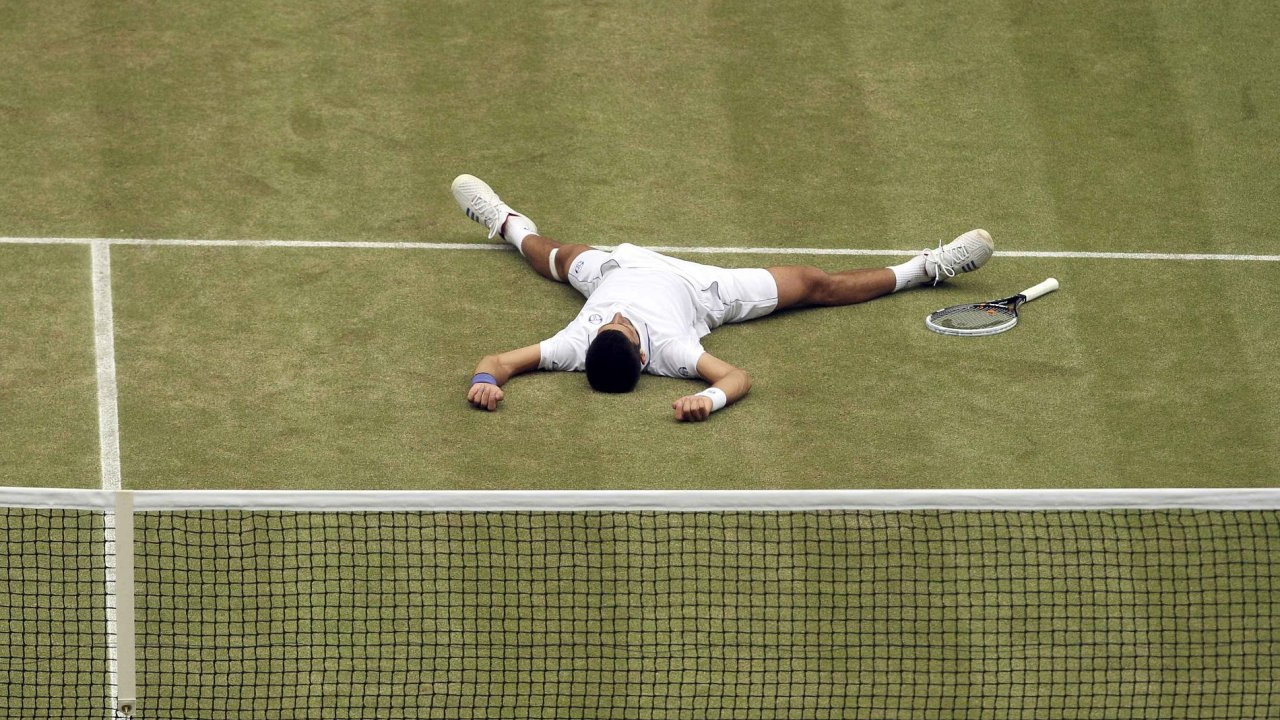 Konec. Po svm prvn triumfu na Wimbledonu ml Djokovi takovou radost, e ochutnal i trvu.
