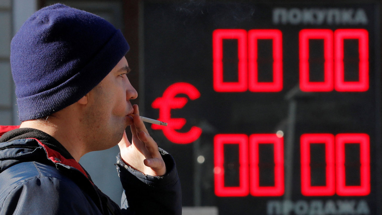 A man smokes as he walks past a currency exchange office in Saint Petersburg