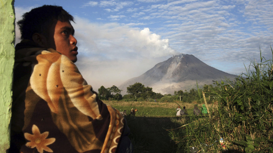 An Indonesian man watches Mount Sinabung as it spews volcanic smoke in Perteguhan
