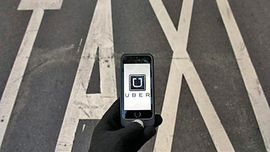 The logo of car-sharing service app Uber on a smartphone over a reserved lane for taxis in a street is seen in this photo illustration taken in Madrid on December 10