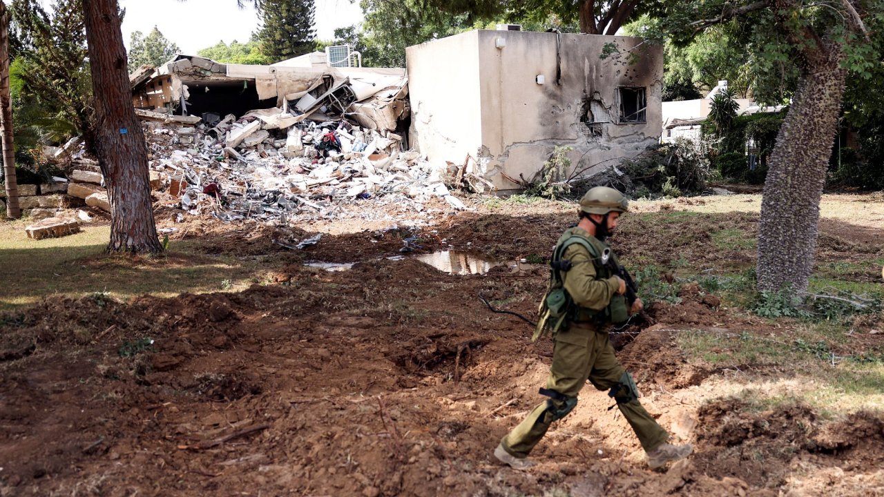 An Israeli soldier walks past a building damaged after rockets were fired from the Gaza Strip into Israel, in Kibbutz Kfar Aza, in southern Israel, October 10, 2023.